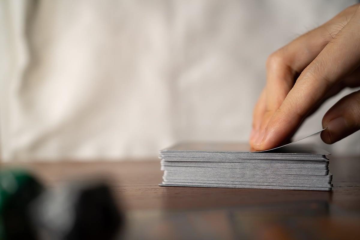 Close up of a hand taking the top card form a deck of cards