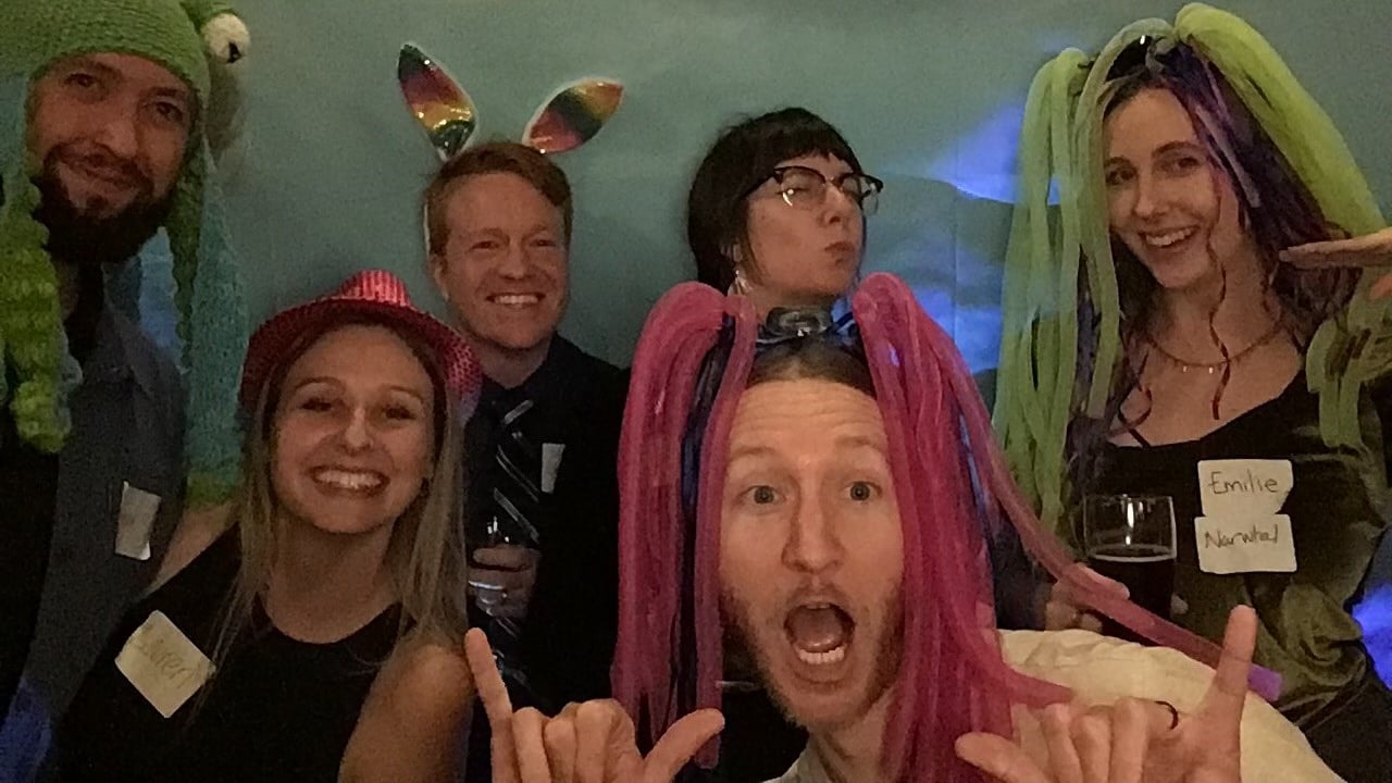 A group of six Clean Power Research employees post for a photo at a team all-hands meeting dressed up in costumes. 