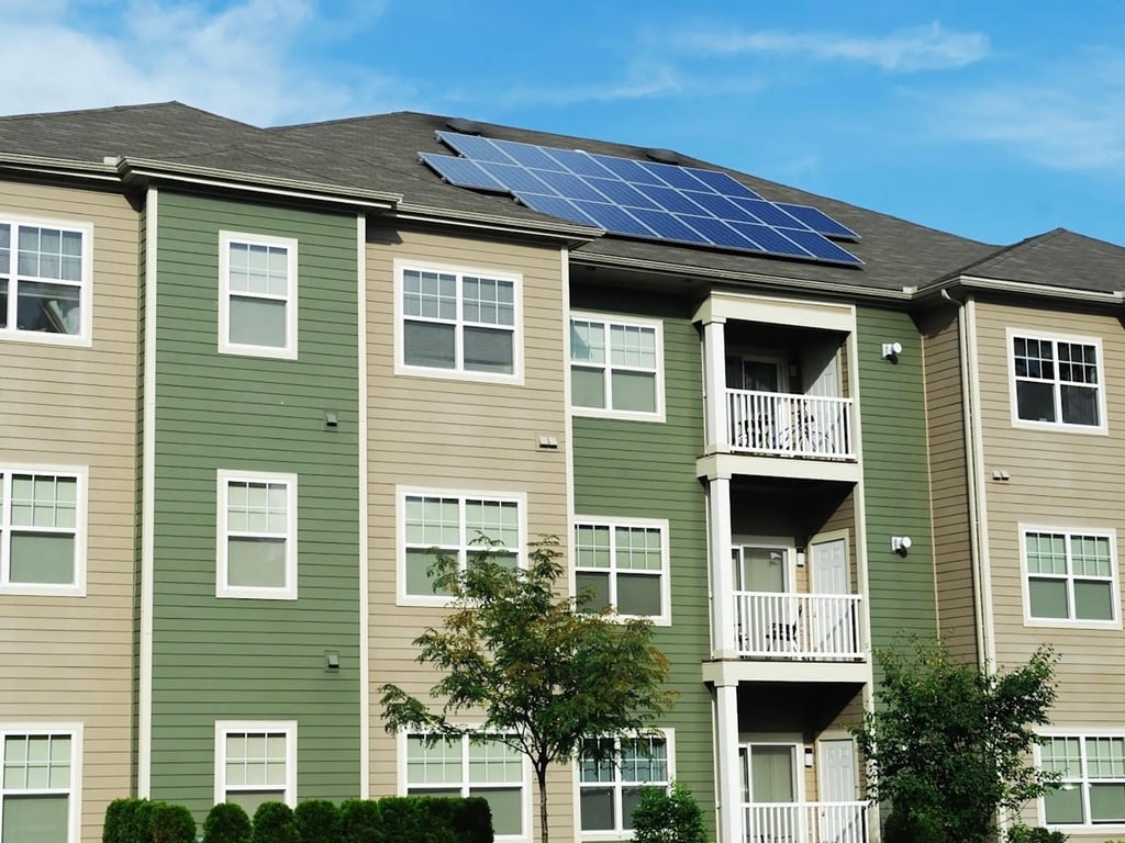 A photo of an apartment complex with solar panels installed on the roof.