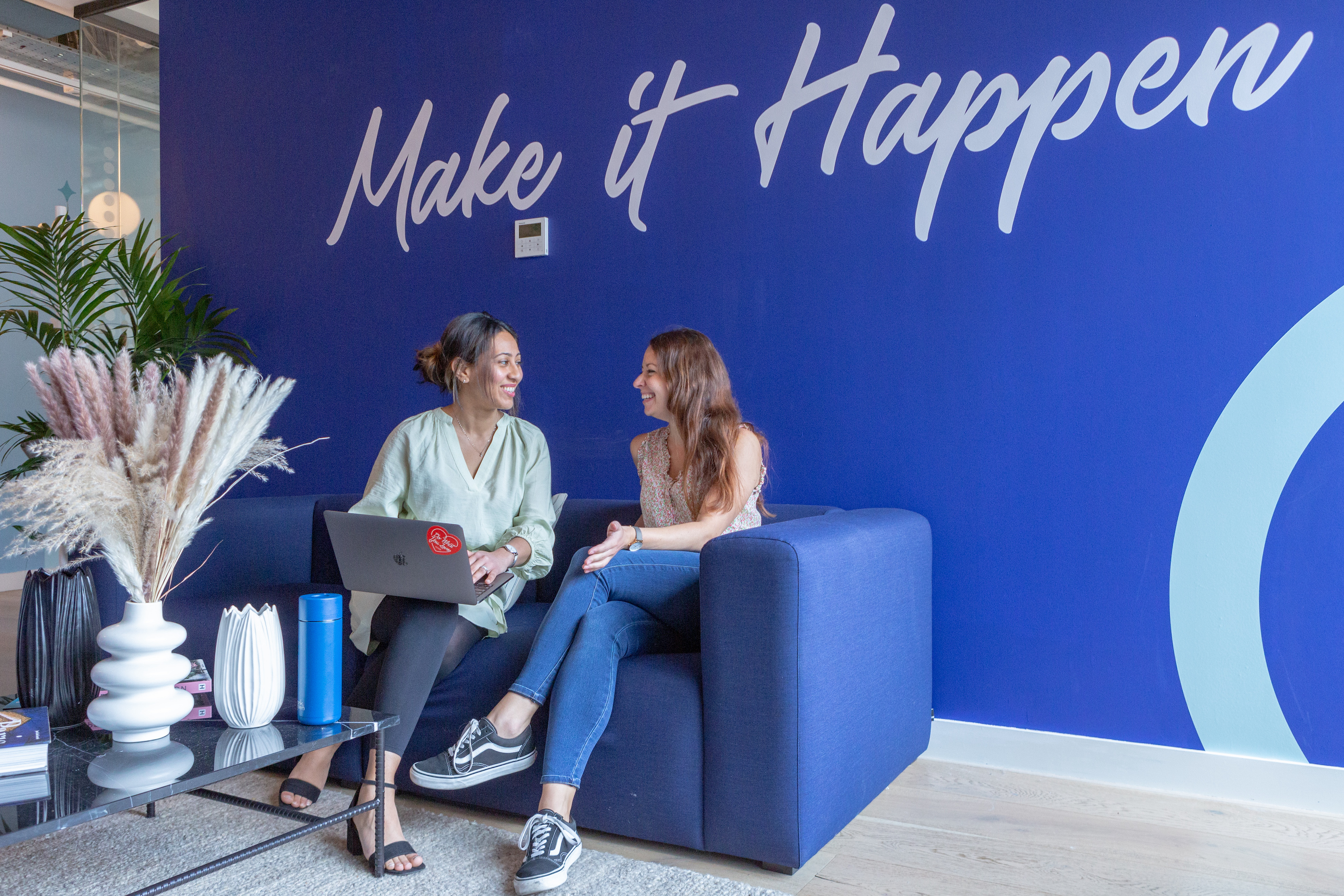 Two members of the Highspot team chat on a couch. 