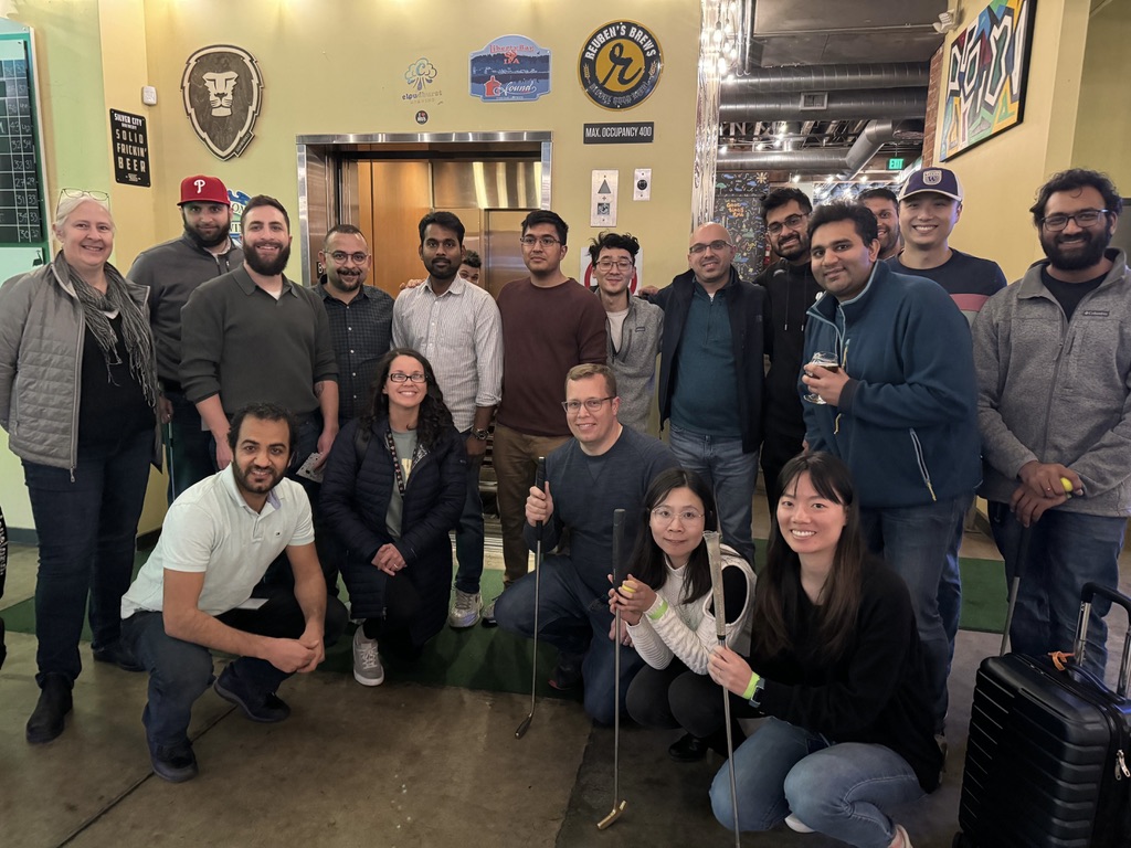 Qualtrics employees pose for a group photo at an indoor mini-golf excursion.