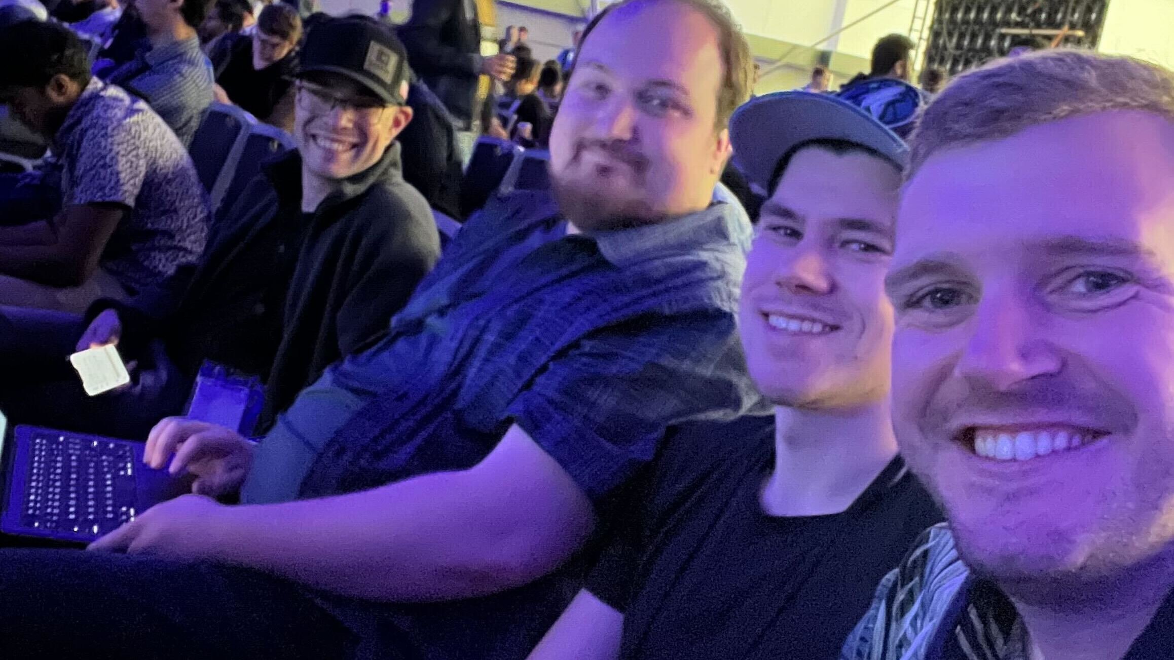 Four Carbon Robotics employees sit in a line with purple light illuminating them in an audience for an event of some kind. 