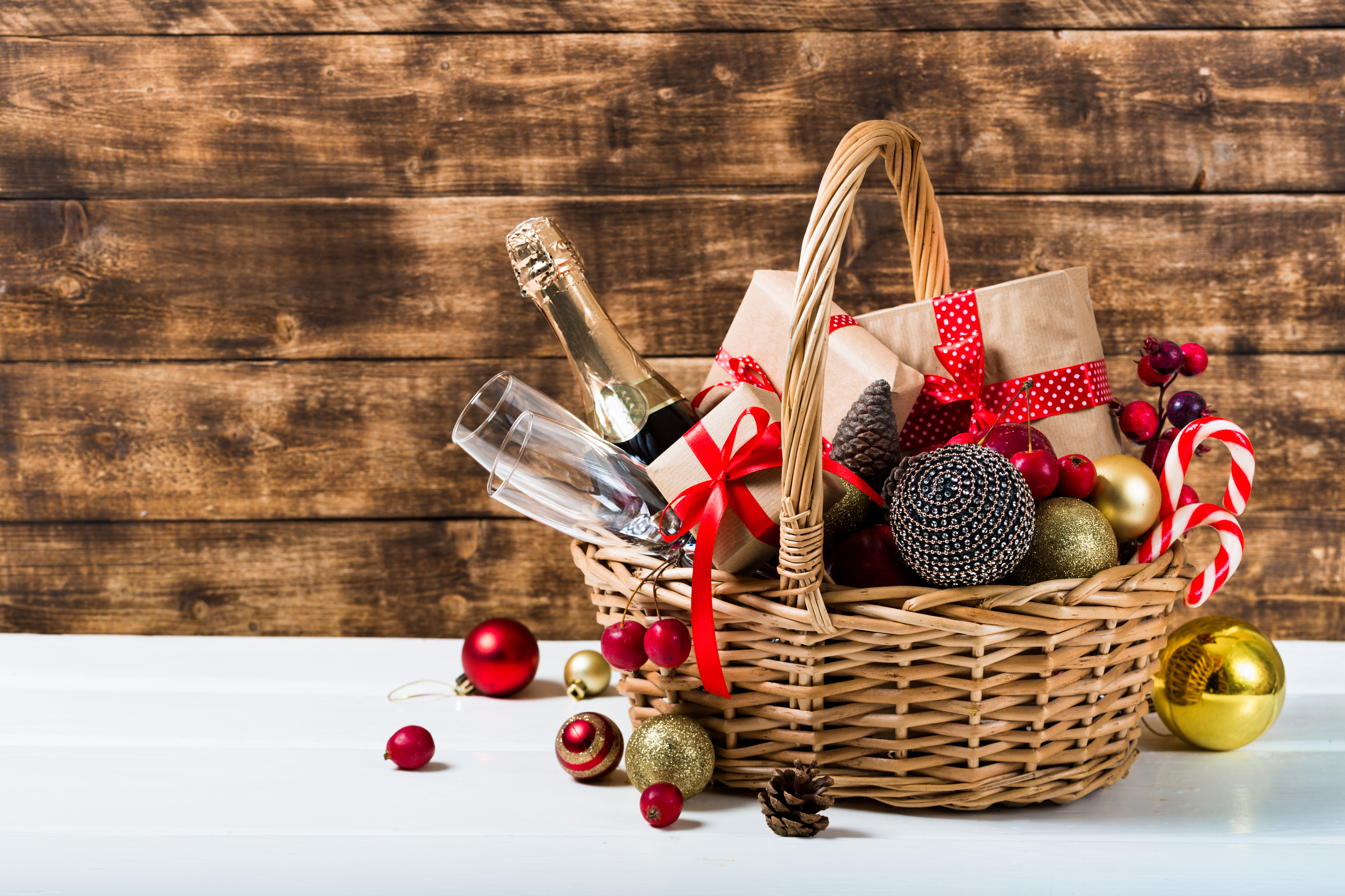 A gift basket with red ribbons, containing wrapped packages, a bottle of champagne and other decorations.